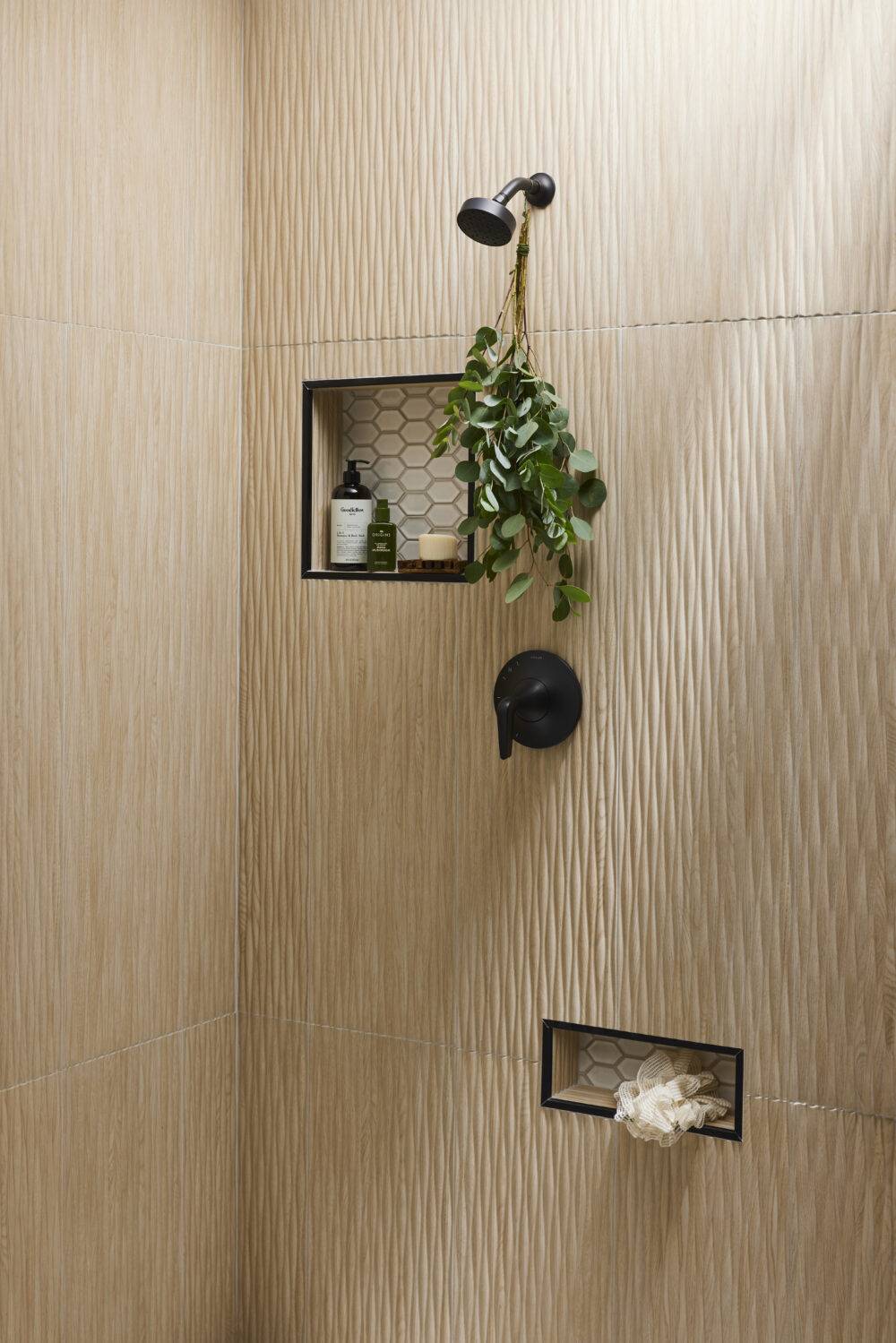A shower with wood-look fluted tile and shower niches that feature elongated hex tile.