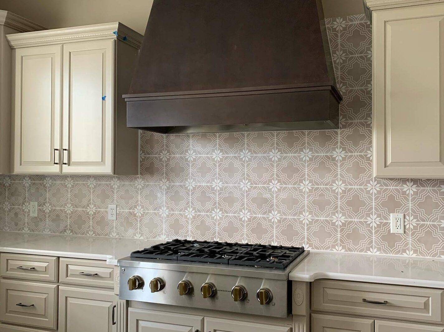 This elegant kitchen features a brown with white patterned tile backsplash.
